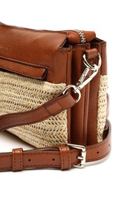 Pruun nahast kott, millel on koobitud õlgedest elemendid, tõmblukuga ülaosa, eemaldatav rihm ja tekstureeritud viimistlus. Hõbedased riistvarad on kaasas.