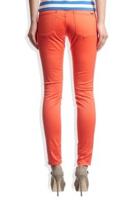 Slim-fit spodnie w jaskrawym pomarańczowym kolorze, wykonane z bawełnianego materiału, z dwoma tylnymi kieszeniami, zestawione z jasnoszarymi szpilkami.