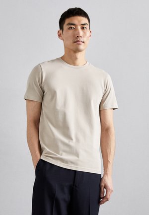 Bežinis trumpas rankovė t-shirt pagamintas iš lygaus audinio su apvalia iškirpte. Prigludęs dizainas su švaria siluetu, derinamas su tamsiais pritaikytais kelnais.