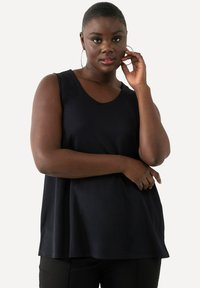 Czarny top bez rękawów z okrągłym dekoltem, o luźnym kroju i gładkiej fakturze. W parze z czarnymi spodniami na zdjęciu.