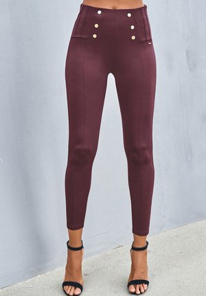 Hochtaillierte bordeauxfarbene Leggings mit goldenen Knopfakzenten und gefalteten Details, enganliegendem Design und glatter Textur.