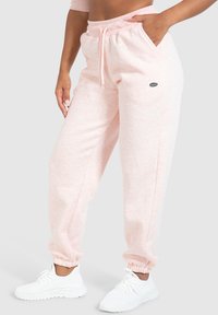 Lichtroze, gemêleerde sweatpants met een elastische tailleband, trekkoord, zijzakken en geribbelde boorden, gecombineerd met witte sportschoenen.