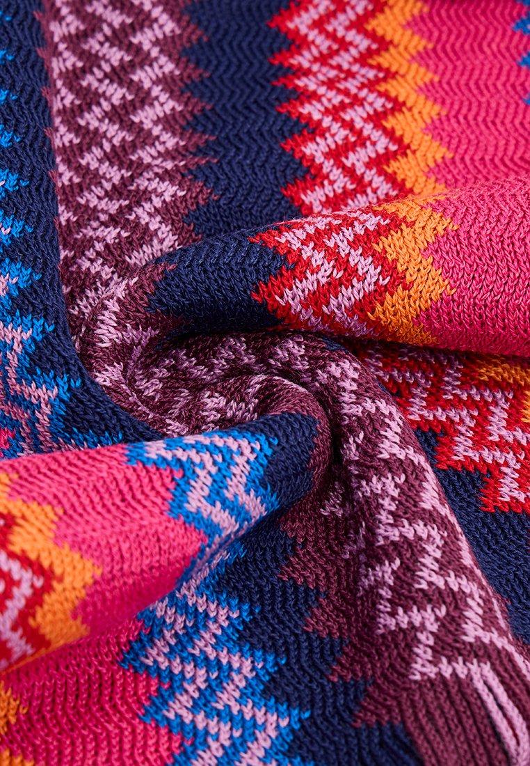 Strickstoff mit Zickzackmustern in lebhaften Farben: Pink, Blau, Rot, Orange und Dunkelpurpur. Weiche Textur mit einem gemütlichen, warmen Aussehen.