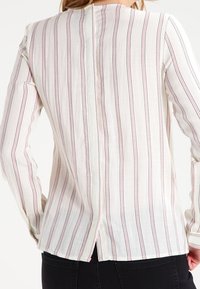 Blusa a maniche lunghe in tessuto leggero, con strisce verticali bianche e rosa, spacco posteriore e scollatura rotonda.