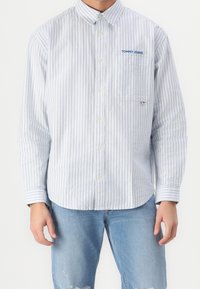 Koszula z długim rękawem w biało-niebieskie paski, z kieszenią na piersi i haftowanym niebieskim logo "TOMMY JEANS".
