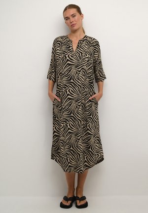 Robe longue et ample avec un motif rayé zèbre noir et beige, fabriquée en tissu doux, dotée d'un décolleté en V et de poches latérales.