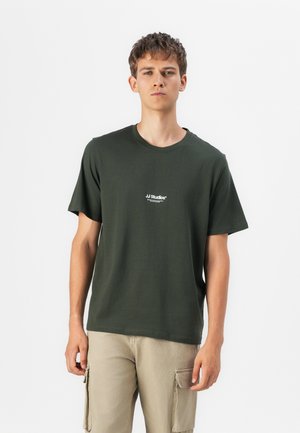 T-shirt en coton vert foncé à manches courtes et col rond. Présente un petit logo blanc "JJ Studios" à l'avant. Design minimaliste.