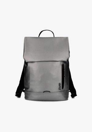 Sac à dos gris avec fermeture à rabat supérieur, poche zippée verticale à l'avant droit, bretelles réglables noires et poignée de transport sur le dessus.