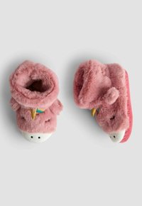 Roze pluche slippers met een zachte, harige textuur, ronde vorm en een witte basis. Kenmerken een speels ontwerp met geborduurde ogen en accenten.