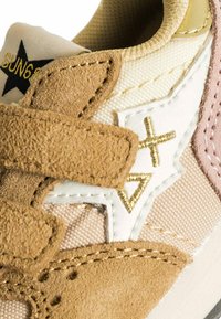 Sneaker con velcro caratterizzato da suede beige, rete crema e accenti rosa pallido. Cuciture dorate in evidenza e dettaglio con logo a stella sulla linguetta.