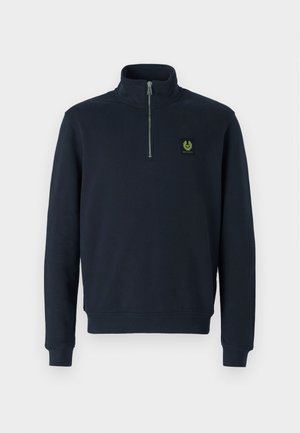 Tumedamast kangast nööpidega dressipluus, millel on kõrge krae, soonikkoes mansetid ja väike roheline logo plaastriga rinnal.