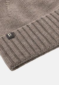 Sivá pletená čiapka s rebrovanou textúrou na spodnej časti a malou čiernou nálepkou s bielym písmenom "B".