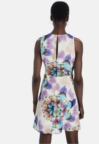 Robe sans manches à imprimé floral avec un motif aquarelle coloré dans des nuances de violet et de bleu, dotée d'une ouverture en forme de goutte dans le dos et d'une taille cintrée.