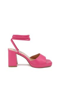 Sandali con tacco a blocco di colore rosa e design a cinturino incrociato. Realizzati in pelle con una texture liscia e punta aperta.