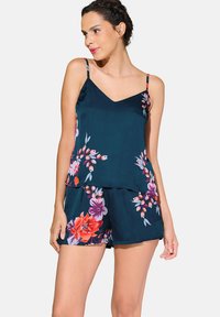 Bloemen tweedelige set met een marineblauw top met een V-hals en spaghettibandjes, gecombineerd met bijpassende shorts die heldere bloemen tonen.