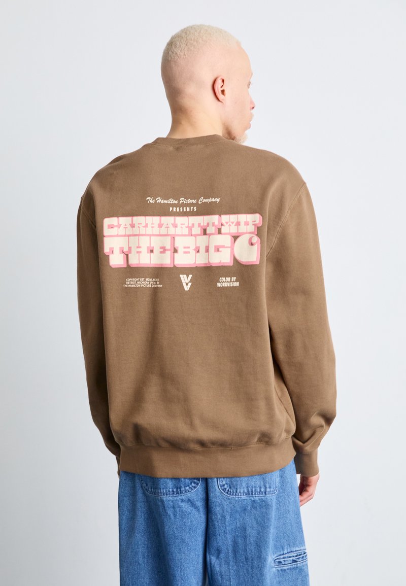 Sudadera de algodón marrón con gran texto rosa en la parte trasera. El diseño incluye logotipos y detalles de la Hamilton Picture Company.