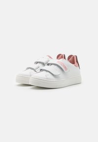 Zapatillas de cuero blanco con detalles en rosa, doble correa de Velcro, detalle de logo circular y suela de goma texturizada. Cuenta con forro interior sintético.