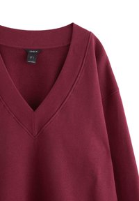 Burgundy v-ringad sweatshirt med ribbad halsringning och avslappnade ärmar. Slät, bomullsrik tyg med en enfärgad nyans och utan mönster.