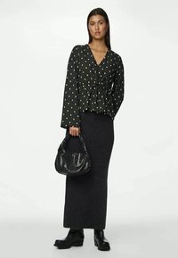 Mustmustega mustriline pluus pikka varrukatega, vöökoht kitsas, koos pika tumeda seeliku ja musta käekotiga. Paksude mustade saapadega on välimus täiendatud.