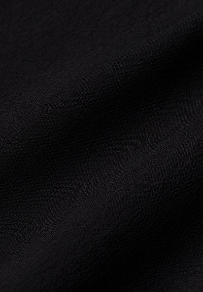 Czarna tkanina o teksturowanej powierzchni, prezentująca miękki splot. Materiał wydaje się lekki i łączy w sobie subtelny wzór.