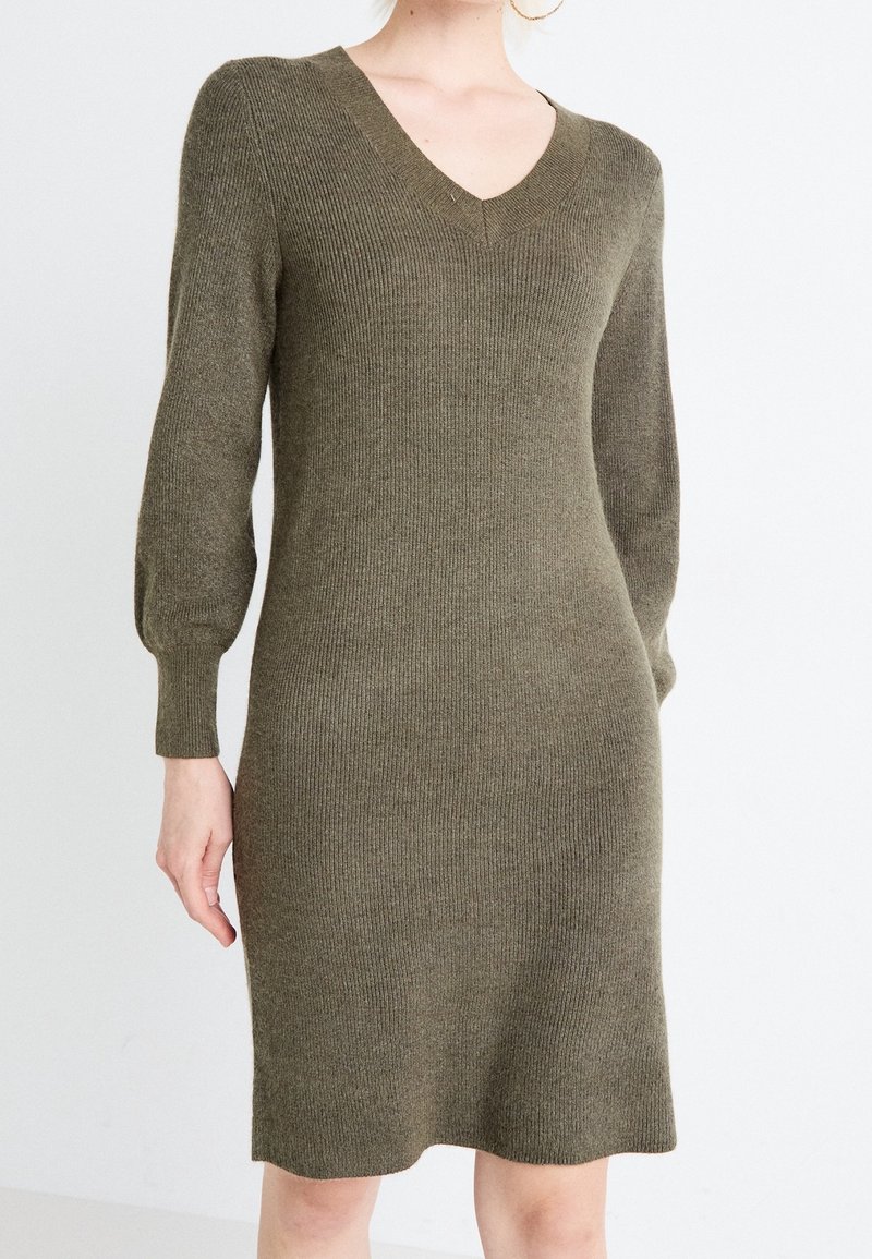 Abito a maglia verde oliva con costine, scollatura a V e maniche lunghe a sbuffo, caratterizzato da una silhouette aderente e orlo all'altezza del ginocchio.