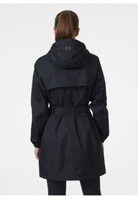 Giacca impermeabile blu navy con cappuccio, vita regolabile con cintura e design con yoke sul retro. Presenta polsini elasticizzati e un tessuto liscio e testurizzato.