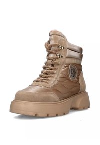 Botte beige à lacets avec un mélange de textures lisses et en suède, col rembourré et une pièce décorative sur le côté. Semelle en caoutchouc épaisse.