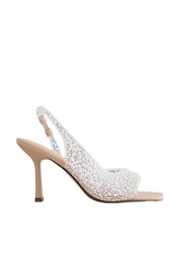 Sandale slingback beige à talon haut avec empeigne transparente ornée de strass et bout carré ouvert.