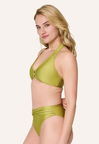 Bikini verde a collare con coppe triangolari e dettaglio a torsione centrale, e parte inferiore a vita alta con accenti laterali arricciati.