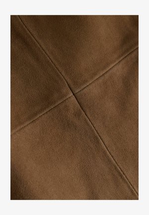 Braun Wildlederstoff mit einer weichen Textur, der ein gesticktes Kreuzmuster aufweist. Die Oberfläche ist matt und gleichmäßig, was das schlichte Design hervorhebt.