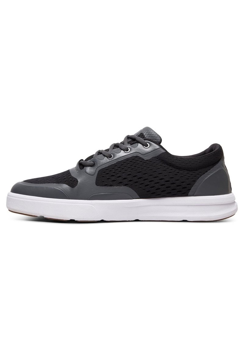 Schwarz-graue Sportschuhe mit einem Mesh-Obermaterial, Gummisohle, sechs Ösen und einer strukturierten Zehenkappe. Das Seitenmuster weist Belüftungsöffnungen auf.