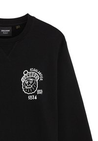 Felpa nera con una grafica bianca di un leone con occhiali e un cappello scozzese. Include il testo "HIGHLANDER" e "1874" sopra la grafica.