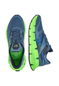 Behacové topánky s tmavomodrou sieťovinou, zelenou EVA podrážkou, modrými detailmi a textúrovanými časťami. Obsahujú šnúrky a polstrovaný interiér.