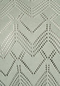 Gaiši zaļa adīta tekstilmateriāla ar ģeometrisku chevron rakstu un caurspīdīgām daļām, izceļot teksturētu un sarežģītu dizainu.