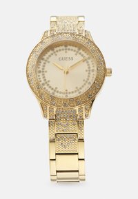 Gouden horloge met een ronde wijzerplaat, versierd met kristallen. Heeft een gestructureerde gouden armband en een gladde lunette met gouden wijzers en markeringen.