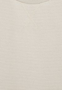 Kremveida teksturēta auduma, kuram ir horizontālas joslas un izšuvumu detaļa apkaklē, kas norāda uz adīšanas struktūru.