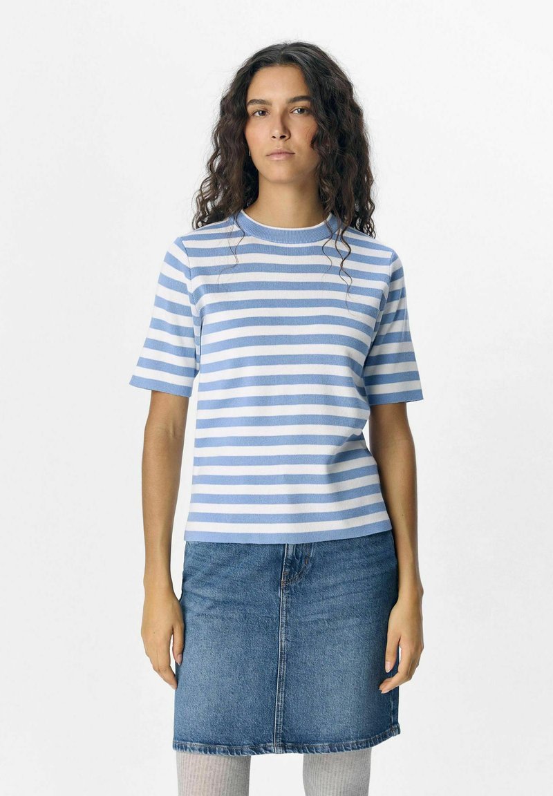 Top de manga corta a rayas en azul claro y blanco, hecho de tela acanalada. Combinado con una falda de mezclilla y medias altas con textura hasta la rodilla.