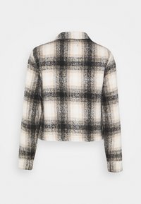 Cropped plaid jacket in black, white, and tan. Textured fabric with a collar, long sleeves, and a boxy shape. No fastenings visible.