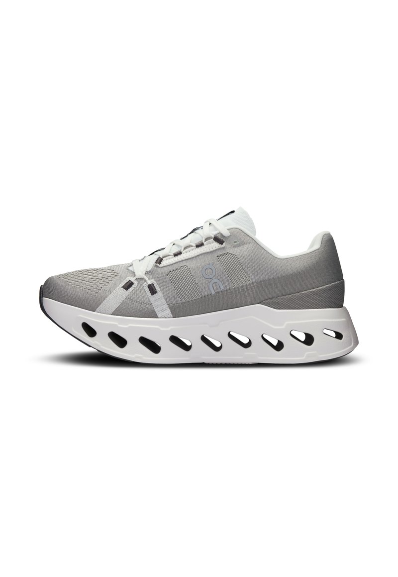 Chaussure de sport grise avec une tige en mesh respirant, des accents blancs et une semelle incurvée dotée d'ouvertures pour la ventilation et la flexibilité.