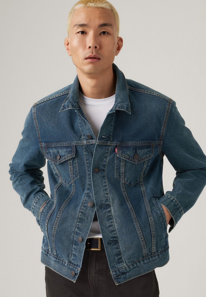 Denimjakke i mellomblått med klassisk design, to brystlommer, knappelukking og litt slitt tekstur.