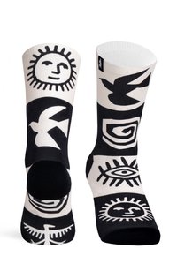 Sorte og hvide sokker med geometriske mønstre, herunder sol-, fugle- og øje-motiver, med ribbet tekstur og kontrasterende sektioner.