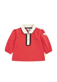 Rotes Langarmhemd mit weißem Kragen, schwarzem Besatz und Verschluss mit drei Knöpfen. Auf einem Ärmel befindet sich ein Teddy-Bären-Patch. Aus weichem Baumwollstoff.