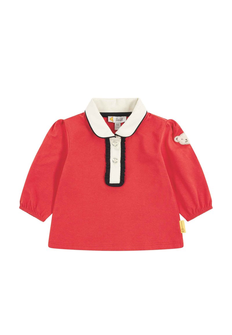 Rotes Langarmhemd mit weißem Kragen, schwarzem Besatz und Verschluss mit drei Knöpfen. Auf einem Ärmel befindet sich ein Teddy-Bären-Patch. Aus weichem Baumwollstoff.