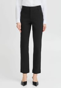 Černé kalhoty na míru se slim fit střihem, s plochým předním dílem, bočními kapsami a hladkým povrchem. Lem je mírně zkrácený.