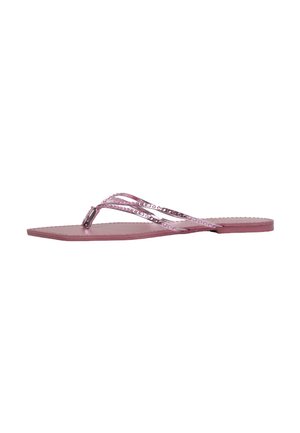 Sandalia plana rosa con tiras finas decoradas con pequeños tachones redondos y diseño de dedo en T sobre fondo blanco.