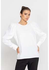 Biała bluzka z bufkami i okrągłym dekoltem, wykonana z gładkiego materiału. Posiada zapinane na guziki mankiety oraz luźny krój.
