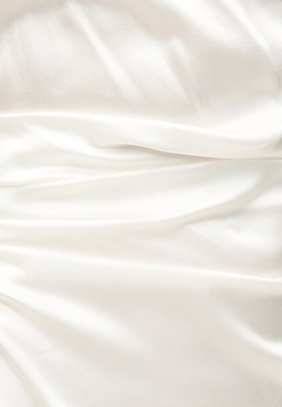 Λευκό μεταξωτό ύφασμα με απαλές, γυαλιστερές πτυχές και απαλά σκιώματα που δημιουργούν μια ρέουσα υφή στην επιφάνεια.