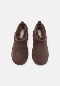 Ghete ankle din suede maro, cu o căptușeală confortabilă din blană, vârful rotund, toc mic și o bandă mică pentru a fi trasă la spate.