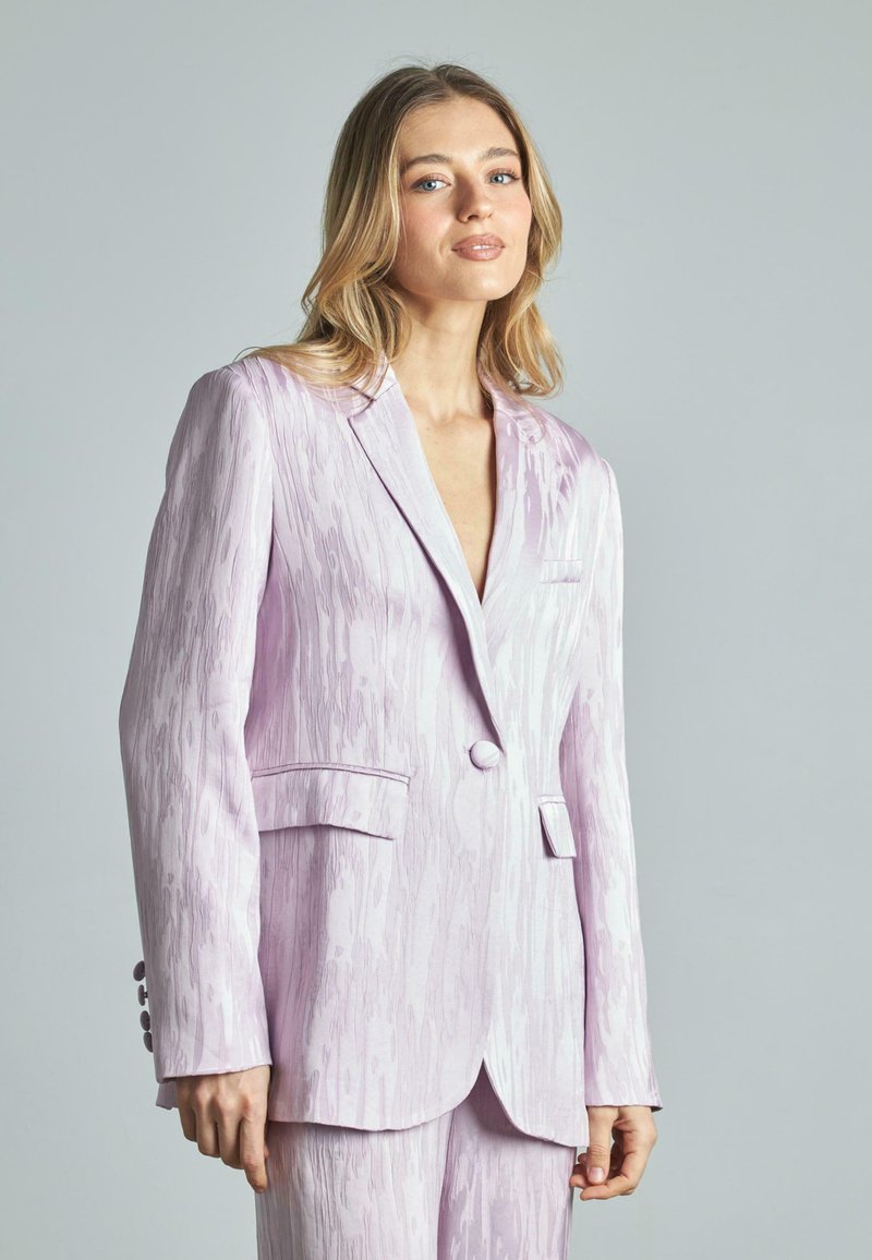 Blazer lilla chiaro con un motivo tessurizzato, revers a scollatura, chiusura a un bottone e due tasche frontali. Tessuto liscio con una leggera lucentezza.