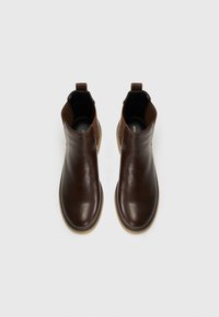 Botas de tobillo de cuero marrón con paneles laterales elásticos, textura suave y suela de goma, con lengüetas en los talones para facilitar su uso.